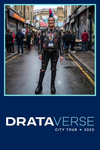 A person with a pink mohawk and studded leather jacket stands in the middle of a graffiti-decorated street during the Drataverse City Tour 2025 event.